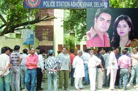 People gather outside the Ashok Vihar police station after a married couple, Kuldeep and Monika (inset), were found dead on Sunday night