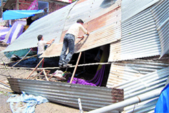Owners try to repair a damaged tin roof of their shop