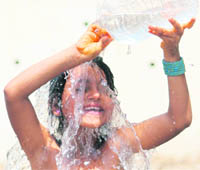 A girl takes a bath to beat the heat near Bawe Road in Jammu on Monday. 