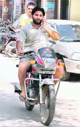 A youth talks on a mobile phone while driving a motorcycle in Ludhiana.