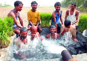 Labourers cool themselves by taking a bath during the scorching heat conditions on the Jalandhar-Nakodar road on Tuesday noon.