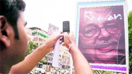 A youth clicks a poster of former Madhya Pradesh Chief Minister Arjun Singh depicted as 'Raavan' by BJP activists for his alleged role in Bhopal gas tragedy, in Indore on Tuesday.