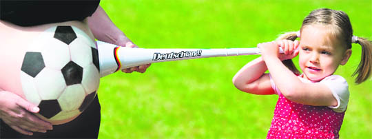 Three-year-old Amy holds a vuvuzela at the football-made-up belly of her mother who is pregnant in the ninth month in Frankfurt an der Oder, eastern Germany. 