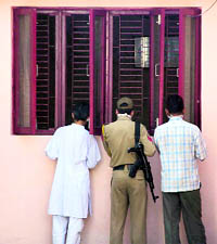Neighbours and a policeman look into the room of a deceased couple at Trikuta Nagar Extension in Jammu on Friday