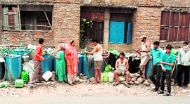 People wait for PHE water tankers in a colony in Jammu on Friday