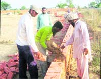 A mason uses mud mortar to construct a boundary wall at Dehlon village near Ahmedgarh. 