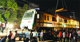 A crane uploads one of four coaches of Delhi Metro on to tracks in New Delhi on Sunday.