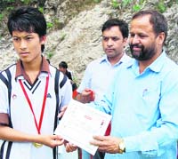 The chief guest of the Mandi Parishad President awards a certificate of merit to a participant at the All-India Summer Cricket Camp on the concluding day 