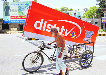 An old man carries billboards of a dish television company in his cart in Dehradun