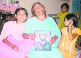A grieving Jagir Kaur shows a photograph of her deceased husband Jarnail Singh