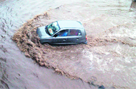 A car crosses a waterlogged road near the bus stand flyover after heavy rain in Patiala on Thursday