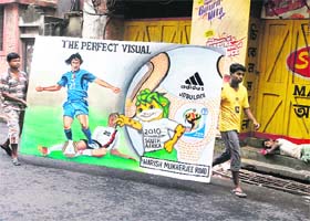 BALL STREET: Workers, carrying a billboard for the 2010 FIFA World Cup, walk past a man sleeping by a shop entrance in Kolkata