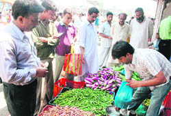 People buy vegetables during hours of relaxation in curfew at Hari Singh High Street in Srinagar on Saturday.