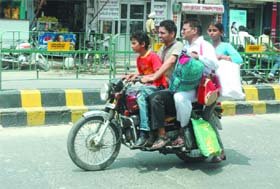 Showing scant regard for traffic rules, four persons ride a bike on the Mall Road in Bathinda
