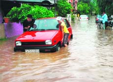 A car owner takes the help of another person to push his car through water in a flooded street in Phase 3B1 of Mohali on Sunday.