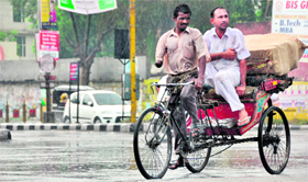 A physically challeged rickshaw-puller carries a passenger in the rain in Ludhiana on Sunday.