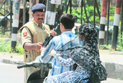 A CRPF jawan stops a couple on a scooter at Lal Chowk in Srinagar on Monday.
