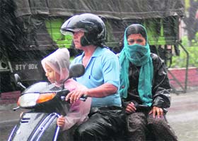 A family braves heavy rains on a two-wheeler in Dehradun