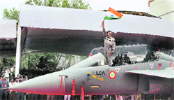 A Navy pilot waves the Tricolour from the cockpit of the LCA trainer during its roll-out ceremony in Bangalore