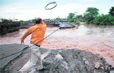 A telecom employee tries to restore a communication link that was snapped following washing away of a section of the Kharar-Banur highway.