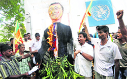 Sri Lankan protesters wave their national flag and burn an effigy of UN Secretary-General Ban Ki-moon outside the UN office in Colombo