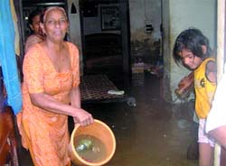 An elderly woman throws rainwater out of her house in Phillaur on Wednesday