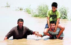People wade through waist-deep water looking for a safe place in Khairpur village in the Ghanaur area on Wednesday
