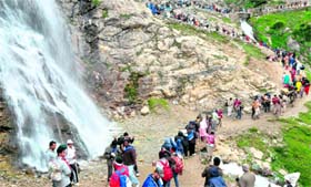 Pilgrims cross a waterfall en route the Amarnath cave shrine near Sheshnag.