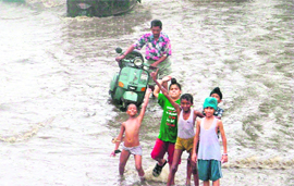 Children have fun while a scooterist struggles to wade through water