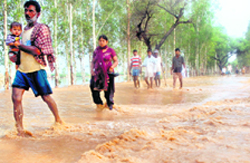 People wade through water in a rural area near Patiala 