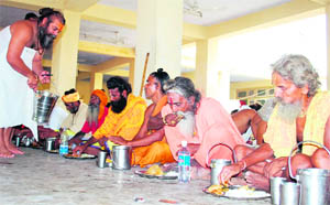 Amarnath-bound sadhus take food at a community kitchen at the Amarnath base camp at Ram Mandir in Jammu on Friday. 