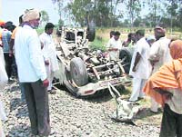 Residents of Ittawali village, near Ferozepore, look at a jeep that was damaged after being hit by a train at an unmanned level crossing on Friday.