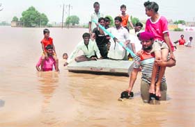 People move to safe areas from flood-hit Badshahpur village in the Patran area on Friday