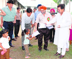State Education Minister Govind Singh Bisht distributes clothes among poor children of Guru Nanak Public Boys Inter-College at the inauguration of the primary section of the school in Dehradun on Saturday. 