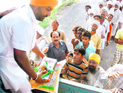 Flood-hit persons stand in a queue to get rations in Adaltipur village in the Dakala area