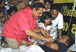 Sri Lankan President Mahinda Rajapaksa offers a glass of water to his Housing Minister Wimal Weerawansa, outside the UN office in Colombo on Saturday.