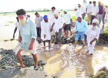 People cross a road damaged with flood water in the Devigarh area near Tangri rivulet on Sunday. 
