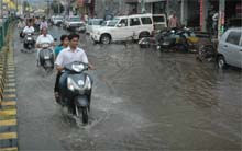 Two-wheeler riders make their way through rainwater accumulated on the Mall road in Bathinda on Monday. 