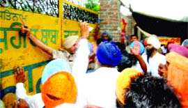 A cop stops activists of the Majha Ex-Servicemen Human Rights Front and Sikh organisations to gain entry to the premises of Bunga Dera Shaheed Baba Tara Singh in Amritsar on Monday.