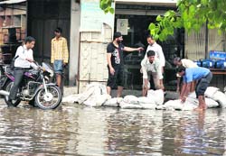 Shopkeepers in the Vishwakarma chowk put sand bags on the road to prevent water from entering their shops in Ludhiana on Monday.