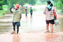 A man carries a pedestal fan to a safe area in one of the flood-hit villages near Patran on Monday. 