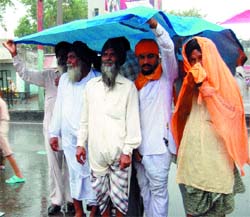 Finally, the rains hit Amritsar. A group of devotees visiting Gurdwara Shaheedan uses a polythene sheet to protect themselves from rain