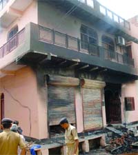 Policemen surround one of the houses that was burnt by a mob protesting the murder of a Delhi University student at Sonia Vihar in north-east Delhi