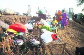 Flood victims with their belongings sit in the open in Sirsa