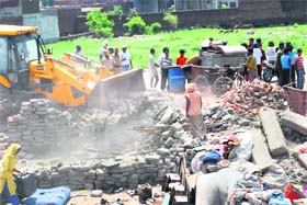 A JCB machine of the municipal corporation demolishes illegal jhuggis near Chand Cinema, Ludhiana