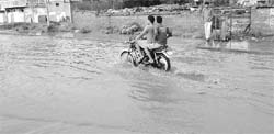 A motorcycle crosses a flooded road following rain in Zirakpur on Thursday.