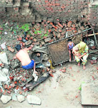 A man in Barna (Kurukshetra) rebuilds his home ravaged by the floods as his wife and children sit on a broken charpoy.