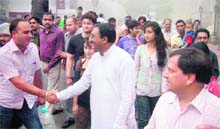    Chief Minister Ramesh Pokhriyal Nishank shakes hand with a tourist from Mumbai on the Mall Road in Mussoorie on Sunday. 