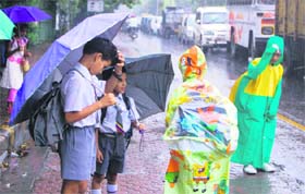 Schoolchildren caught in the rain in Dehradun on Monday.