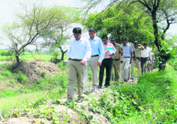 Deputy commissioner Ajit Joshi along with other officers inspects a rainwater drain near Juan village